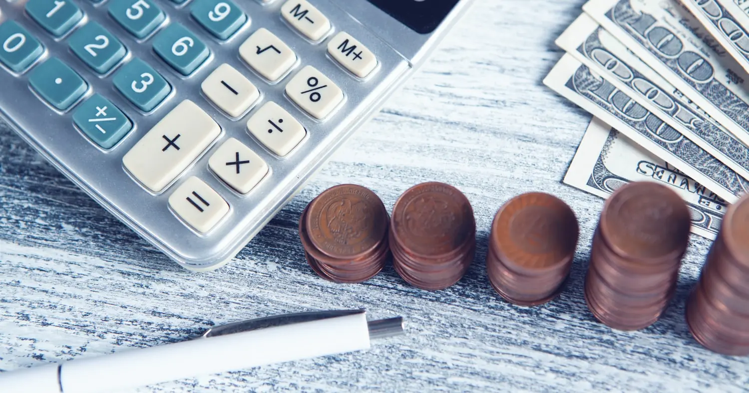 Calculator, pen and banknotes on a table