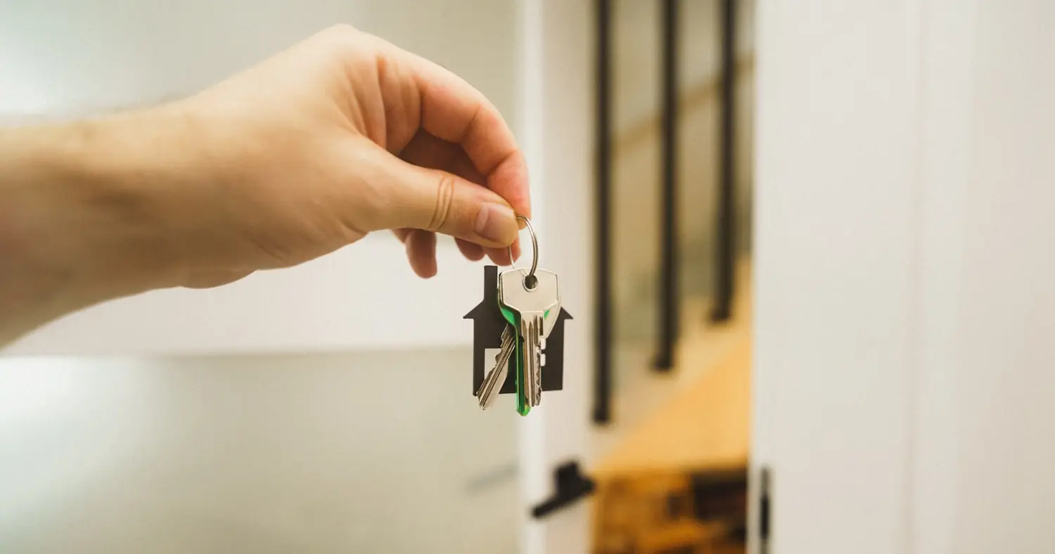 Hand holding a key in front of a door