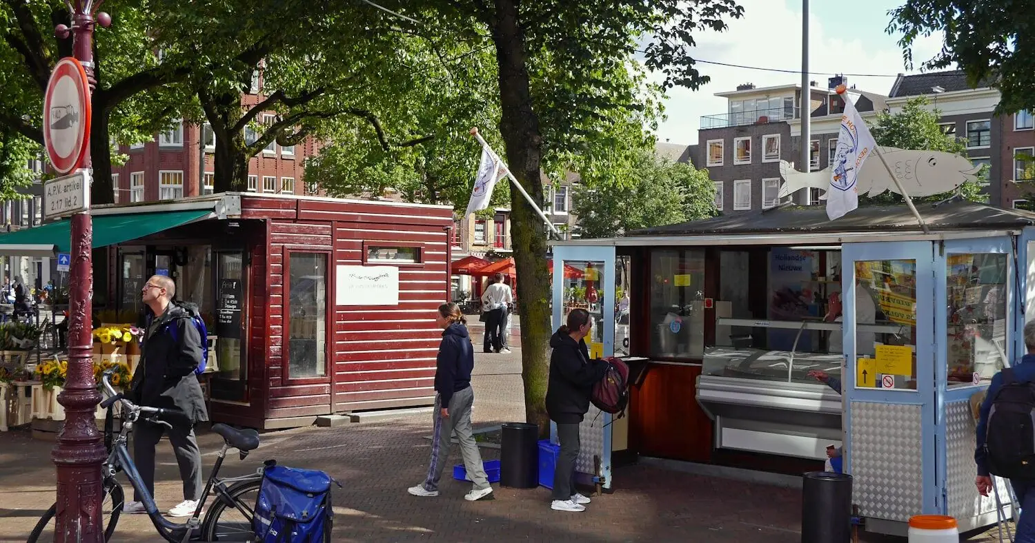 Shoppers walking past street market stalls in Amsterdam